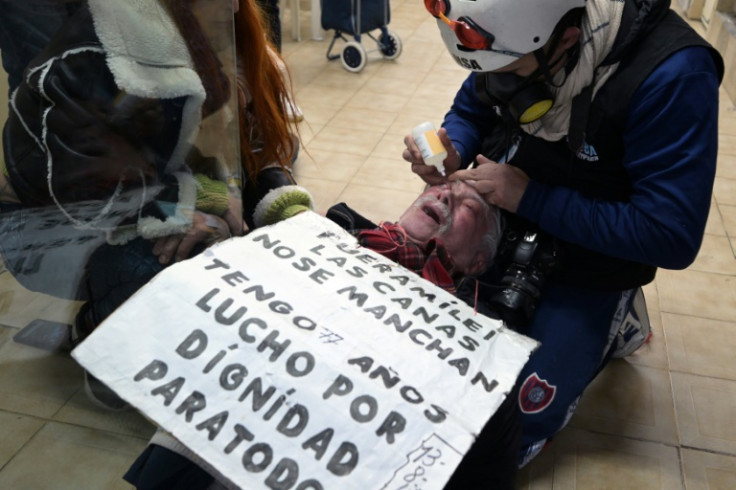 A rescuer cares for an elderly man affected by tear gas thrown by federal forces