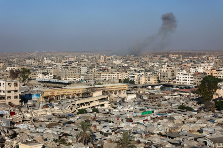 View of a makeshift displacement camp at a sports stadium in Gaza City, as smoke billows during Israeli strikes