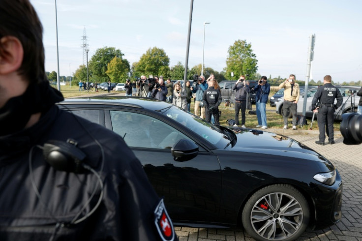 The car carrying Christian Brueckner is driven out of the prison, flanked by police vans and watched by a large group of media
