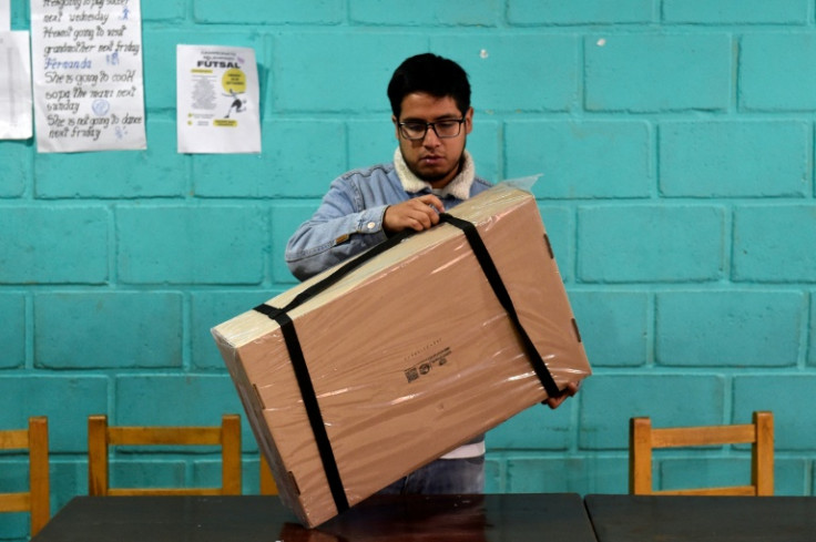An electoral staffer opens a box containing voting materials before polls open for the presidential runoff election in La Paz on October 19, 2025