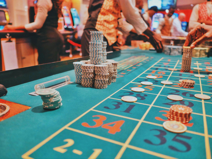 A casino roulette table with poker chips and players in