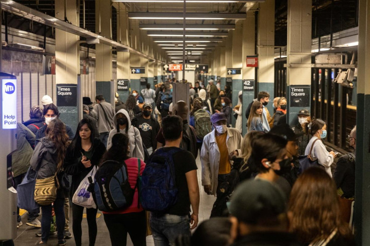 Commuters stand on a platform in Times Square station, after a shooting at a subway station in Brooklyn borough, in Manhattan, New York City