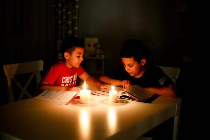 Children study by candlelight during a power outage, at home in  Tripoli